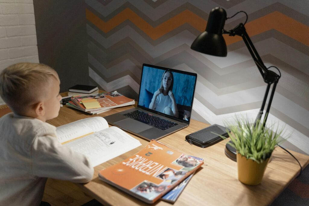 A child engaged in online learning with a laptop and educational materials. — education for grandchildren Utah