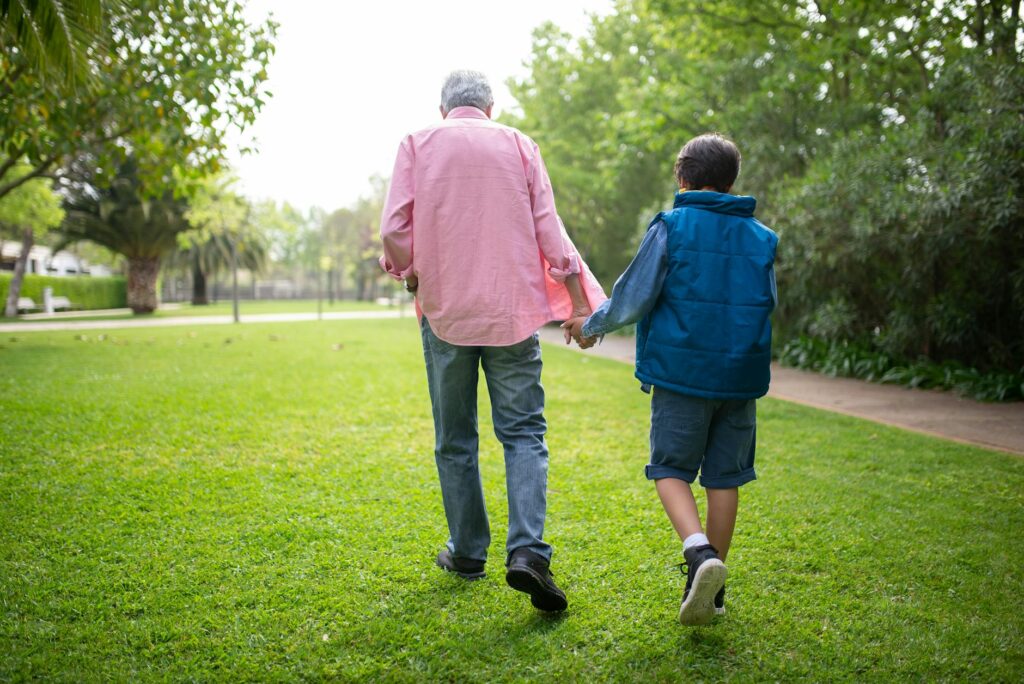 A grandparent playing catch with their grandchild in a park, showcasing outdoor engagement activities. — keeping grandch…