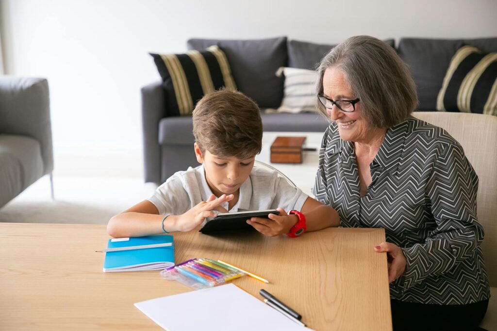Image of a grandparent helping a child with homework using a tablet, emphasizing family learning. — technology support g…