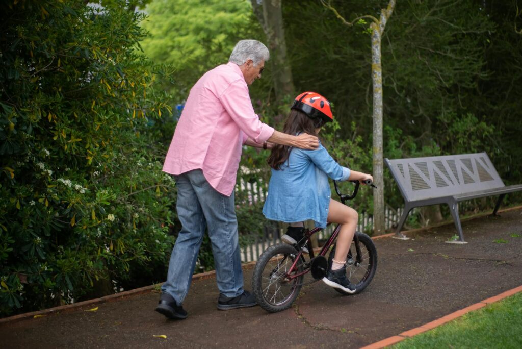 A grandparent teaching a child to ride a bike in a safe, open space. — benefits of grandparents Utah