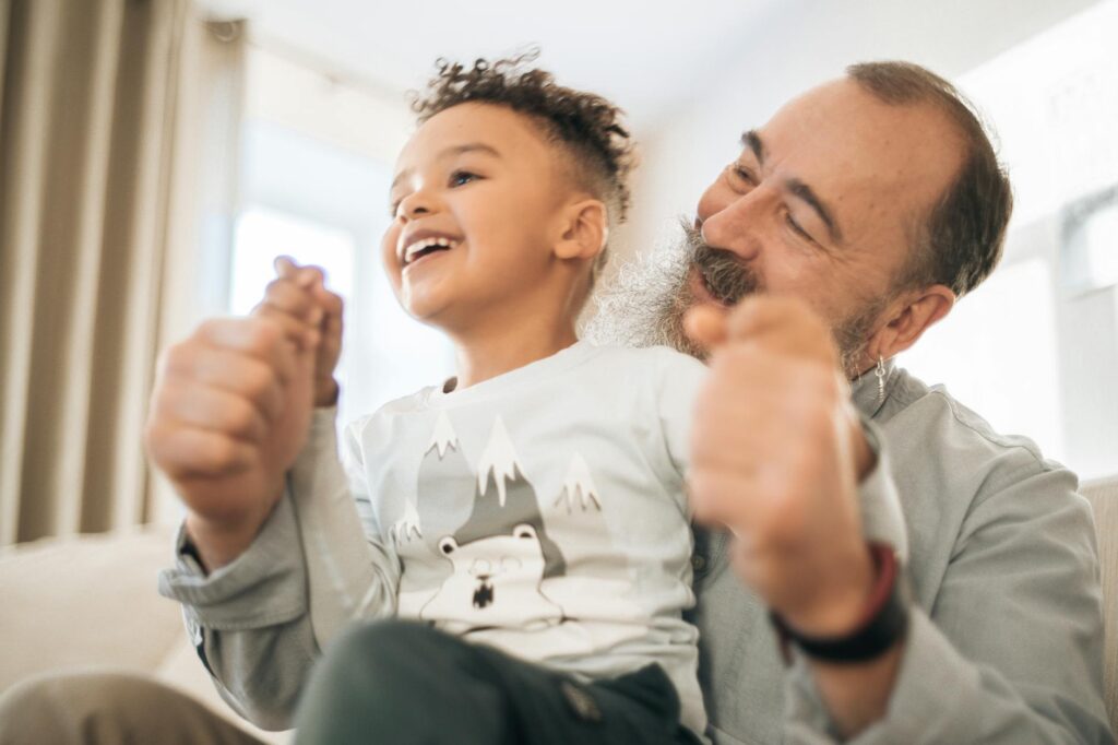 A happy grandparent playing with their grandchild in a park, representing family support. — financial assistance grand f…